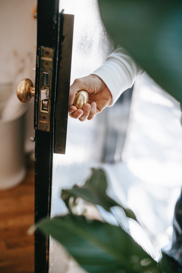Photo de Photo de Charlotte May: https://www.pexels.com/fr-fr/photo/crop-personne-ouvrant-la-porte-du-batiment-au-soleil-5825395/ y